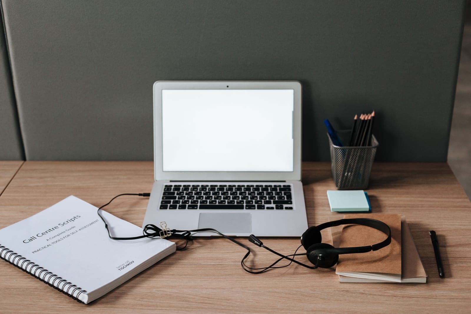 A desk with a felt privacy panel, laptop and headset
