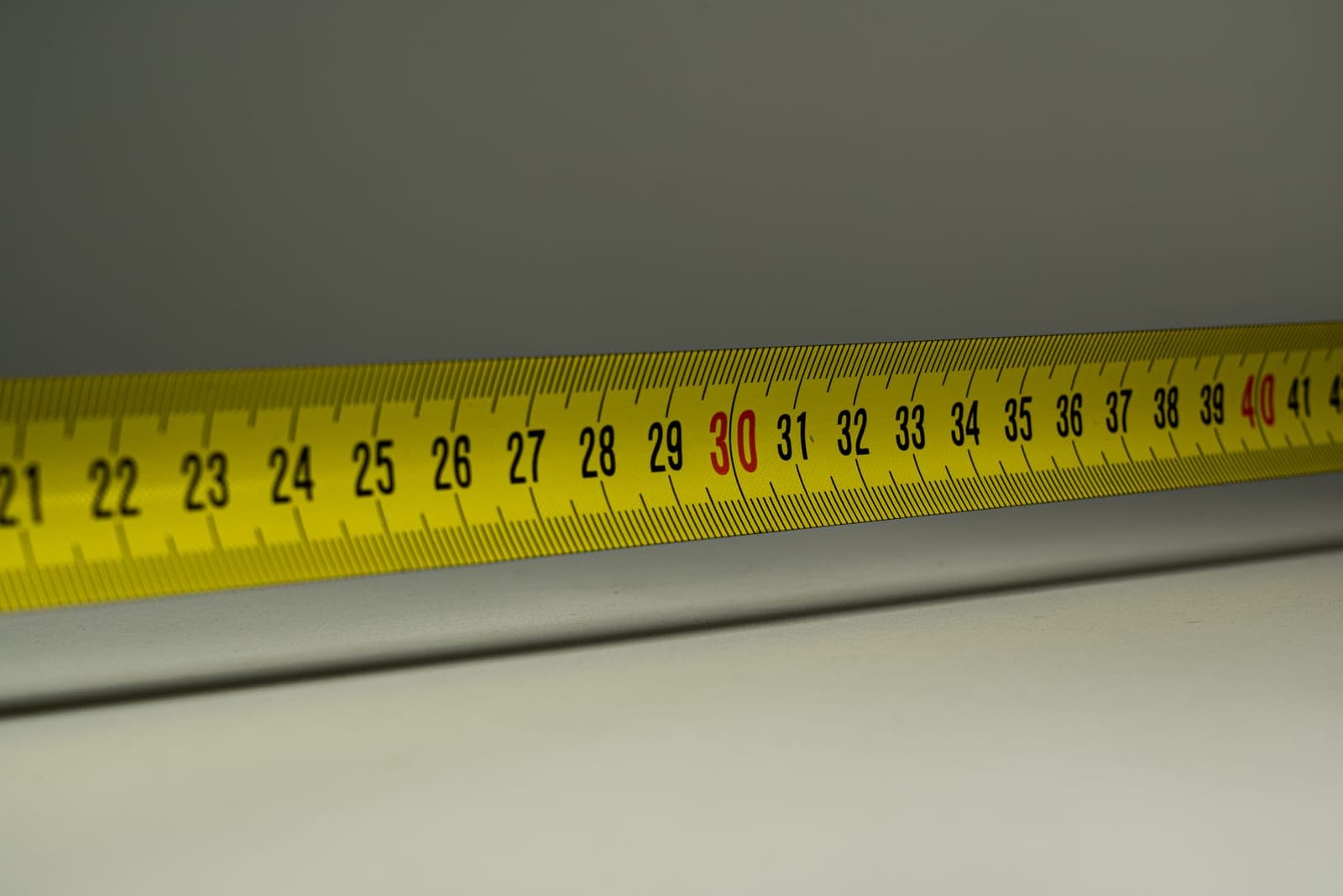 A measuring tape being used against a piece of furniture