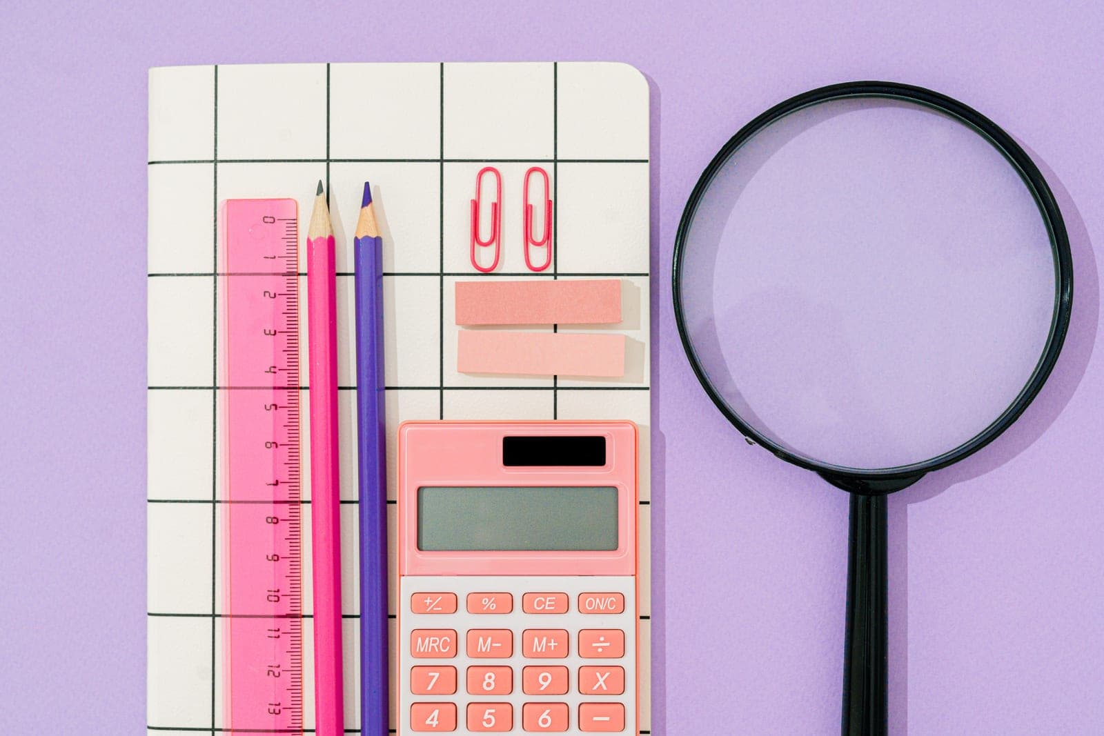 A calculator, notebook and pencil on a desk beside a tape measure