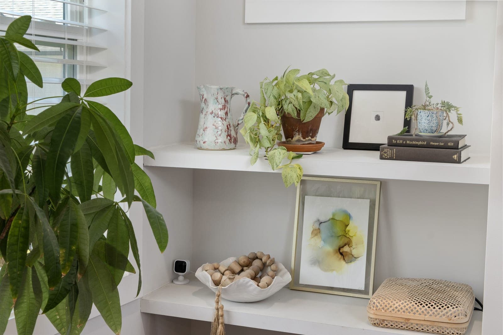 Styled office shelves holding books, boxes and a plant